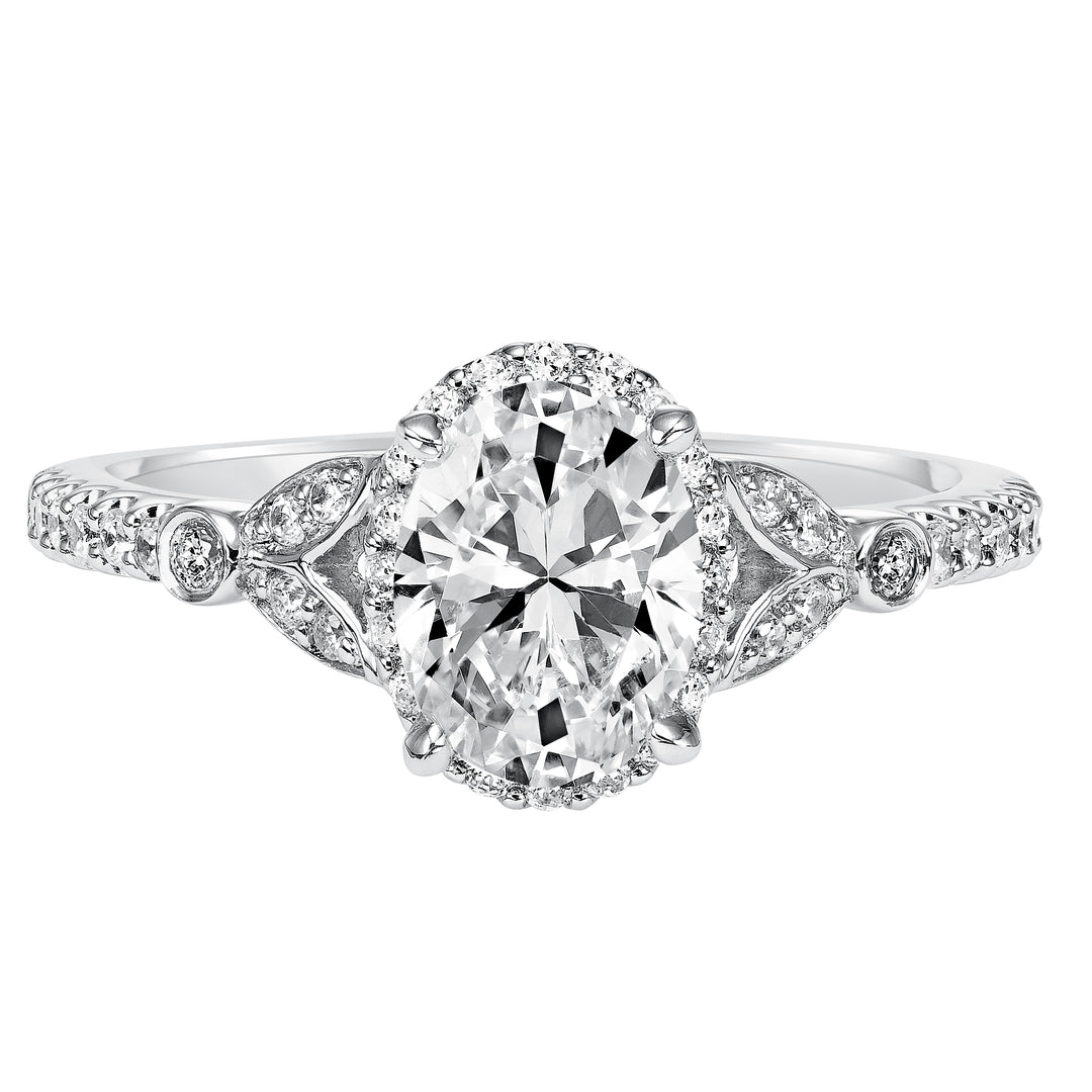 This romantic and beautiful engagement ring features an oval cut diamond accentuated by a prong set diamond halo and petal-inspired band design.  Center Stone is not included.