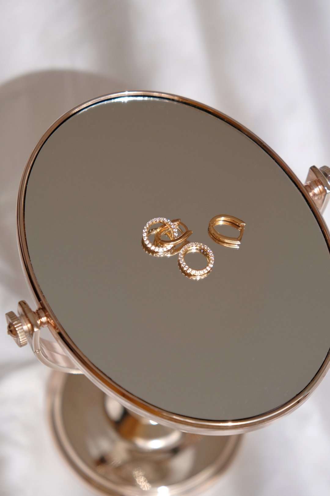 diamond earrings placed on a desktop mirror